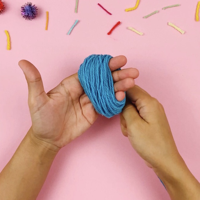 Wrapping wool around a hand to start the pom pom making process.