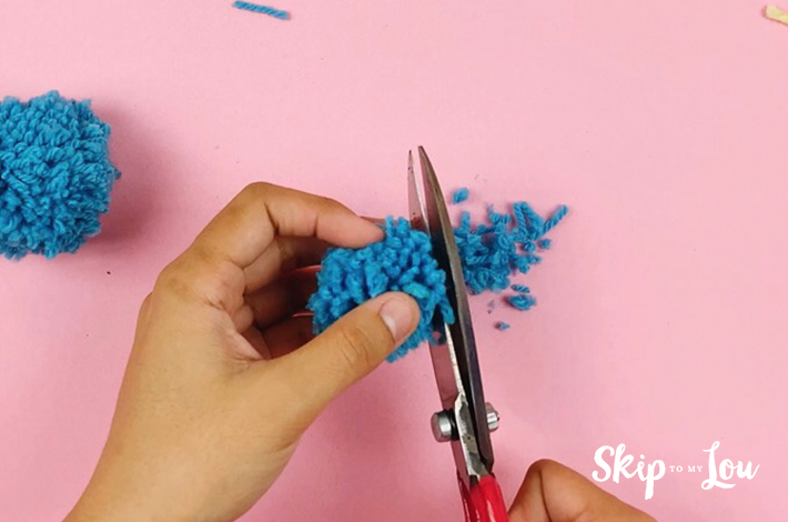 Cutting the wool ends to one length to finish the pom pom.