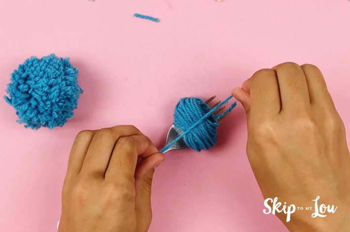 The pom pom is secured by tying a knot.