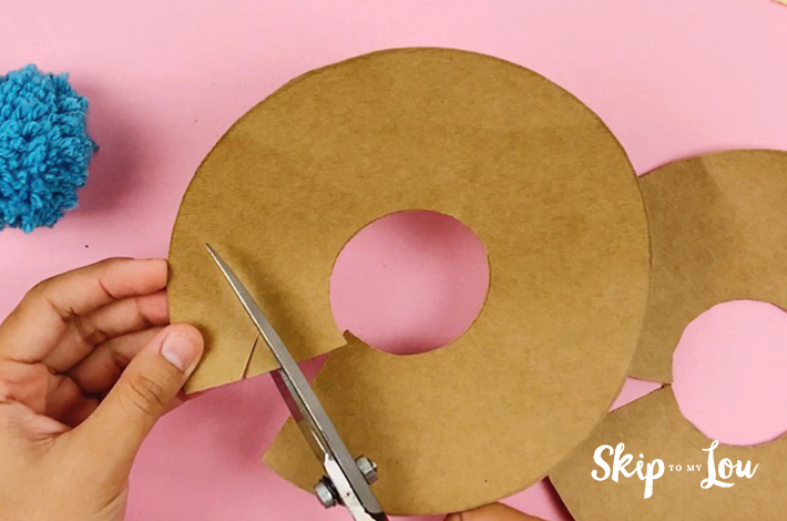 Cutting the first cardboard ring with a pair of scissors.
