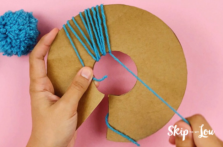The pom pom starts forming when wool is wound round the cardboard.