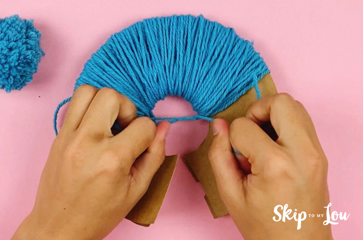 The two ends are tied together to secure the pom pom.