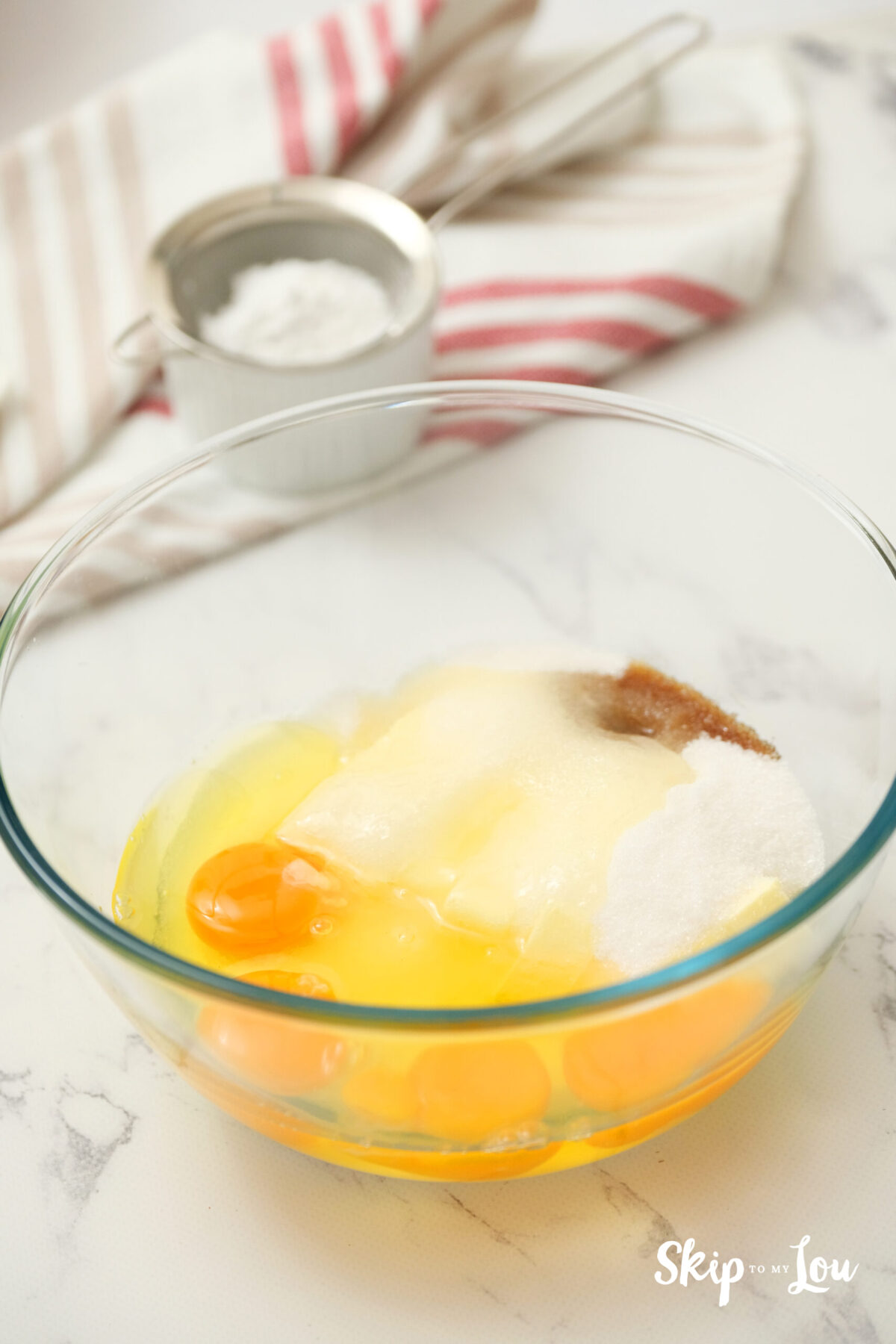 A bowl of ingredients: butter, sugar, vanilla extract, and eggs.
