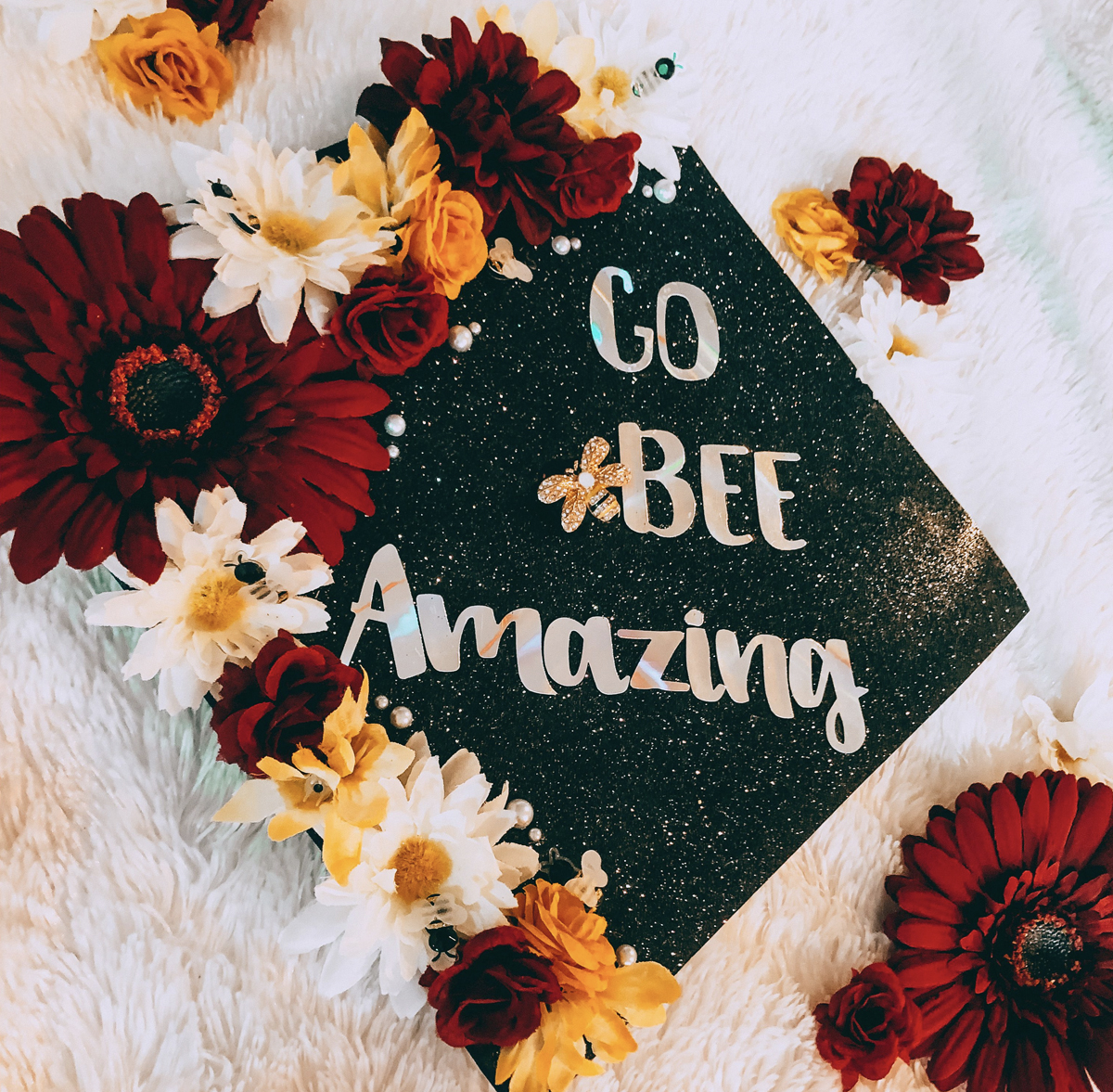 Graduation cap decorated with flowers and quote "go bee amazing"
