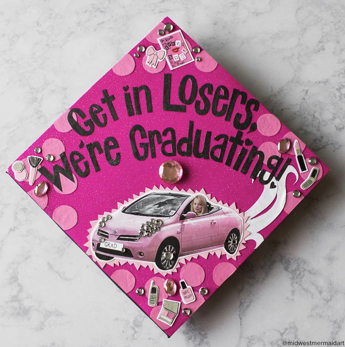 Pink graduation cap with a Mean Girls theme and quote that says Get in losers, we're graduating