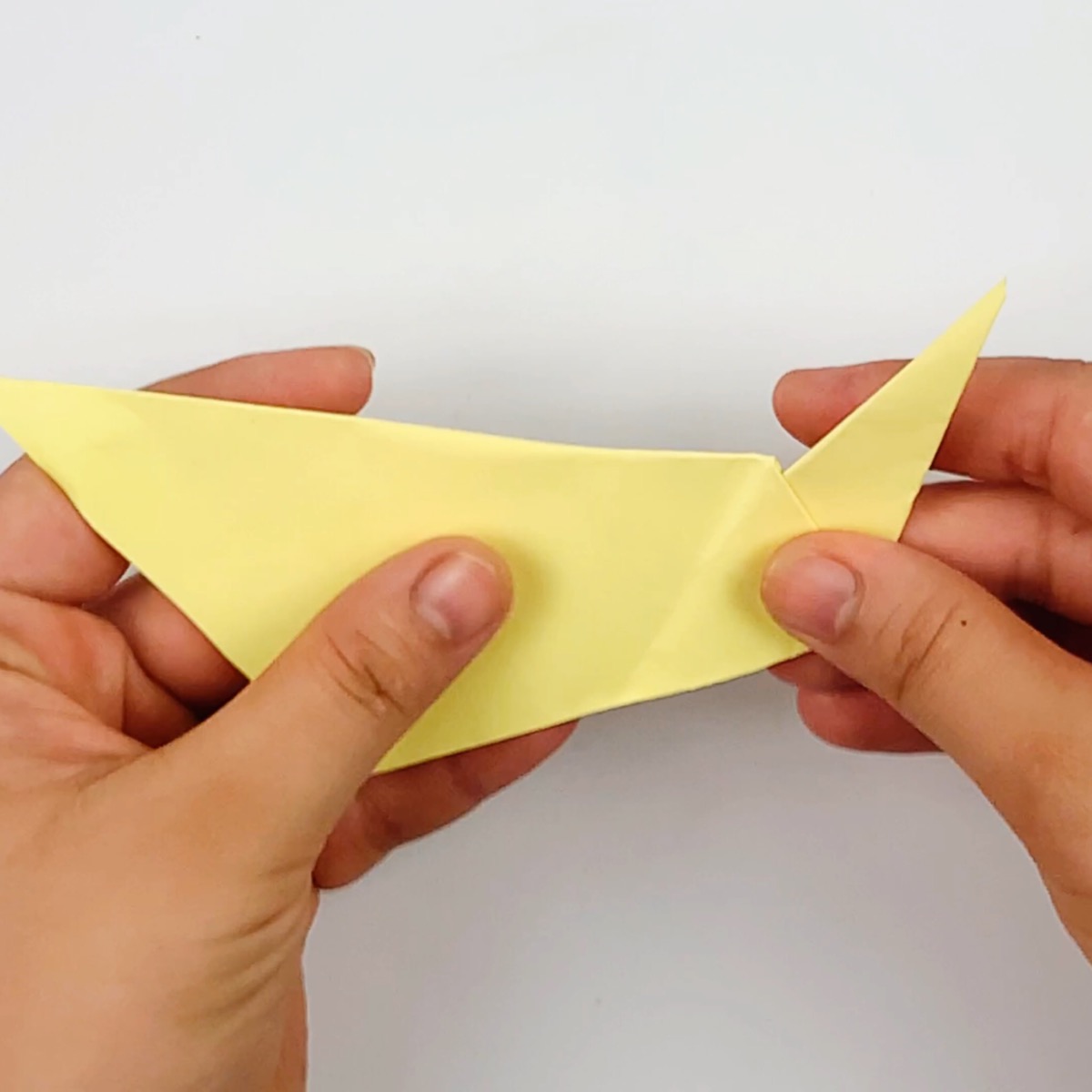 Securing the fold to keep the origami cat tail in place.