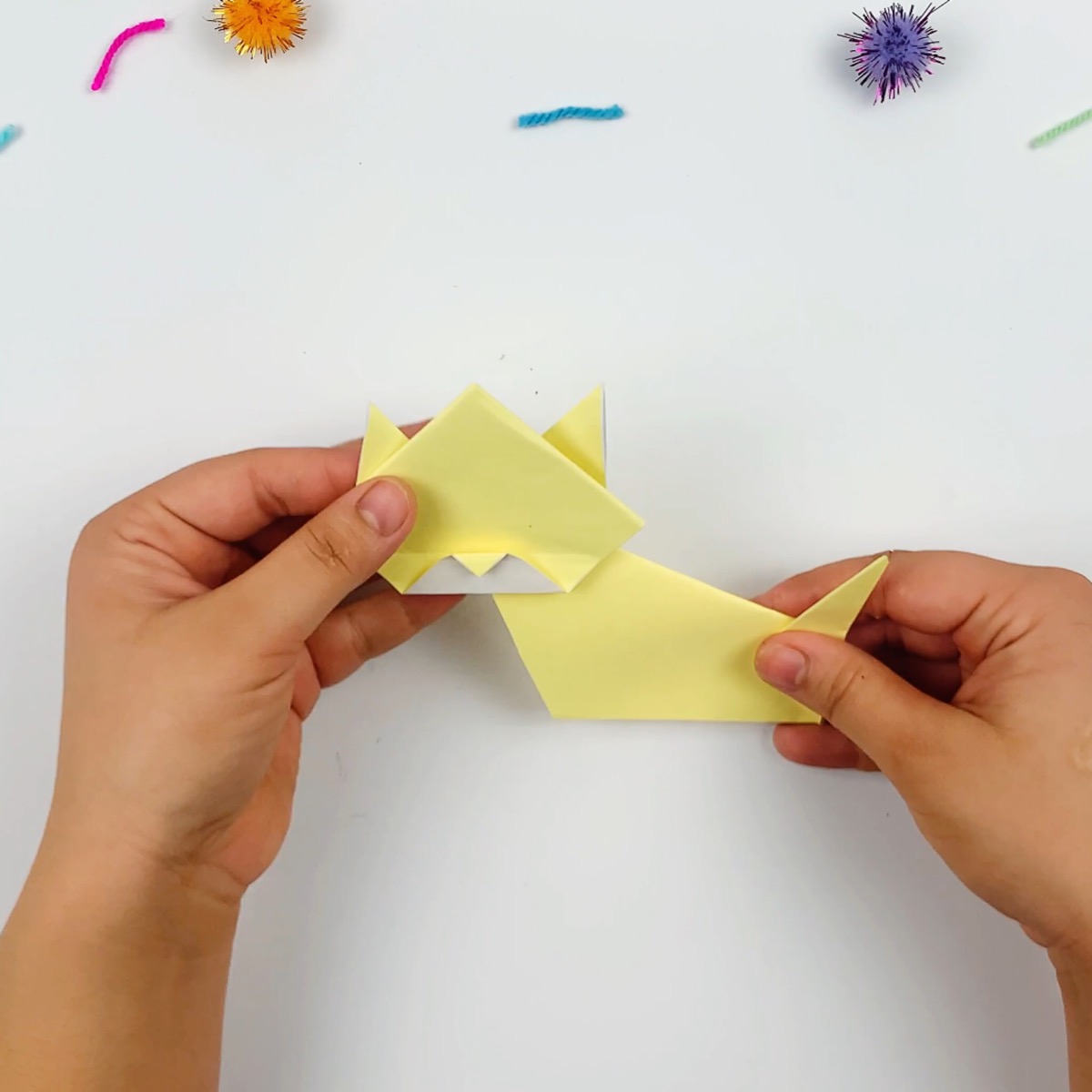 Attaching the head of the origami cat to the body.