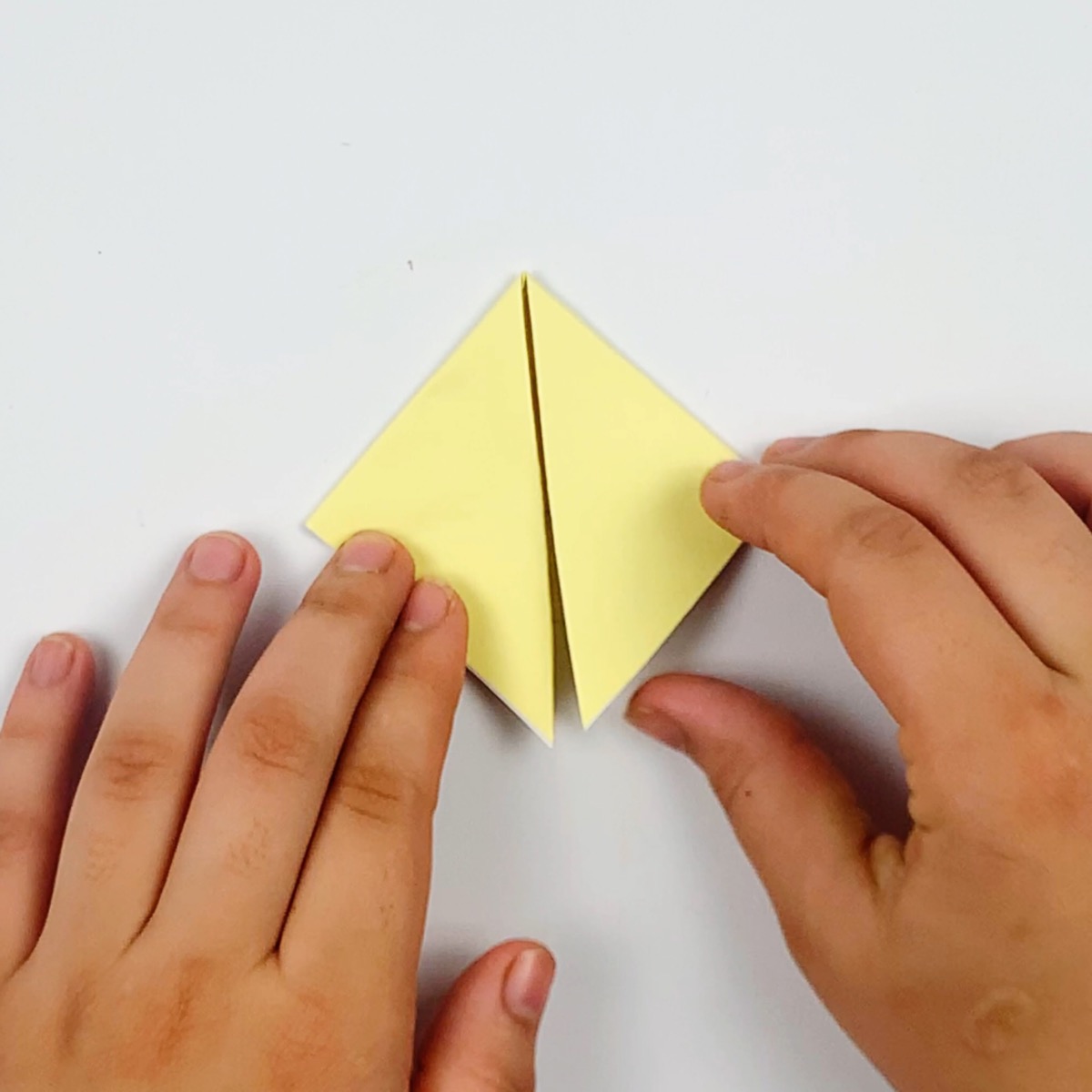 Flaps are folded downwards as the first part of making the origami cat's ears.