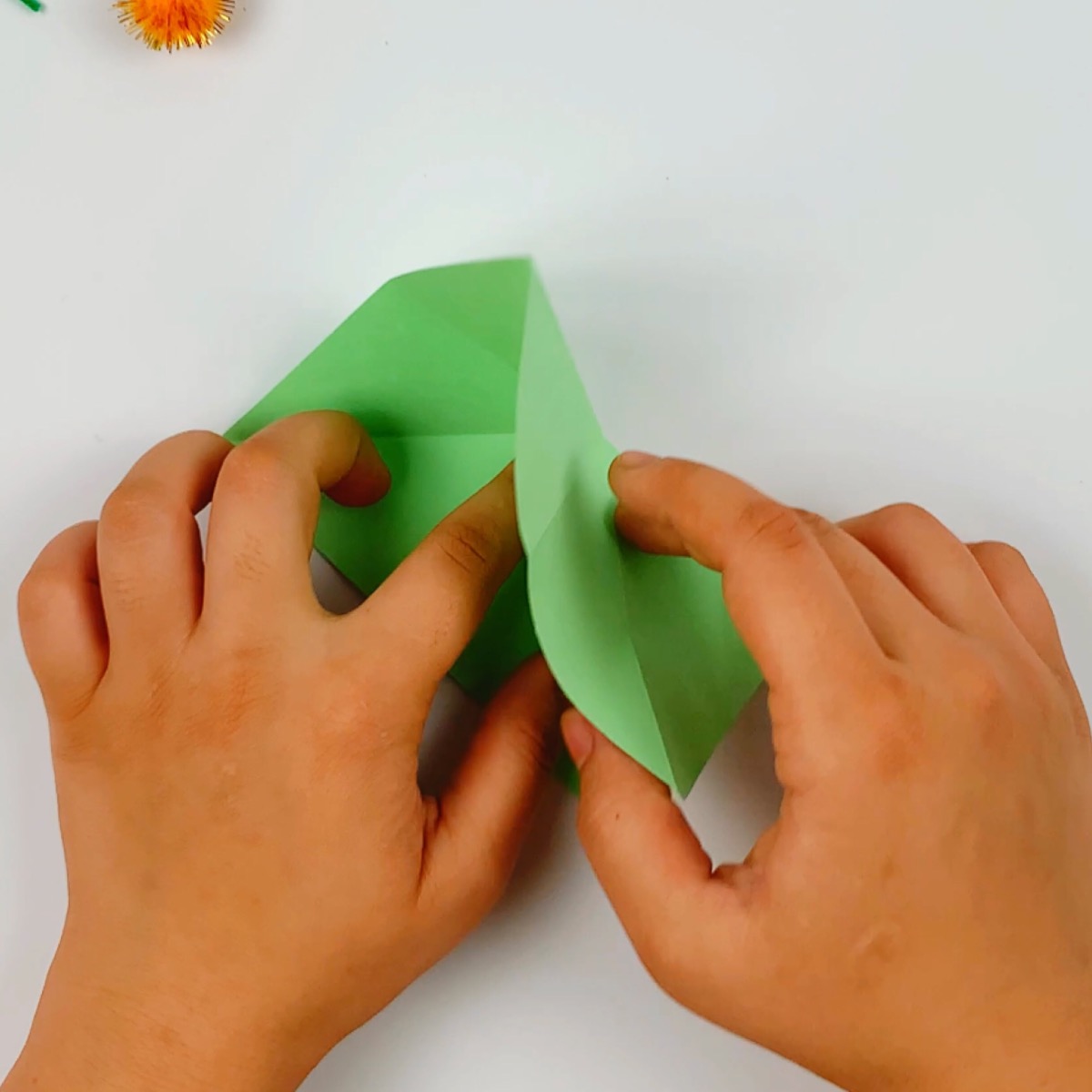 The square green paper is folded to form the body of the fish.