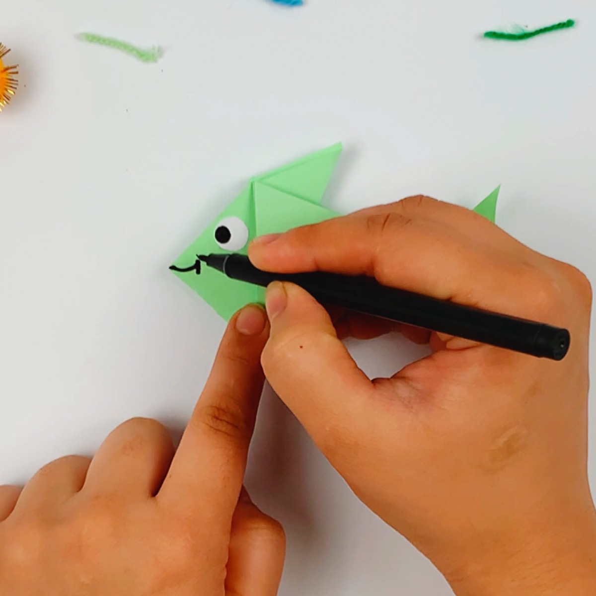 The face of the origami fish is drawn in.