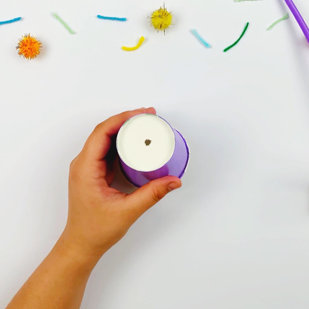 Positioning a whole in a second paper cup with a pair of scissors.