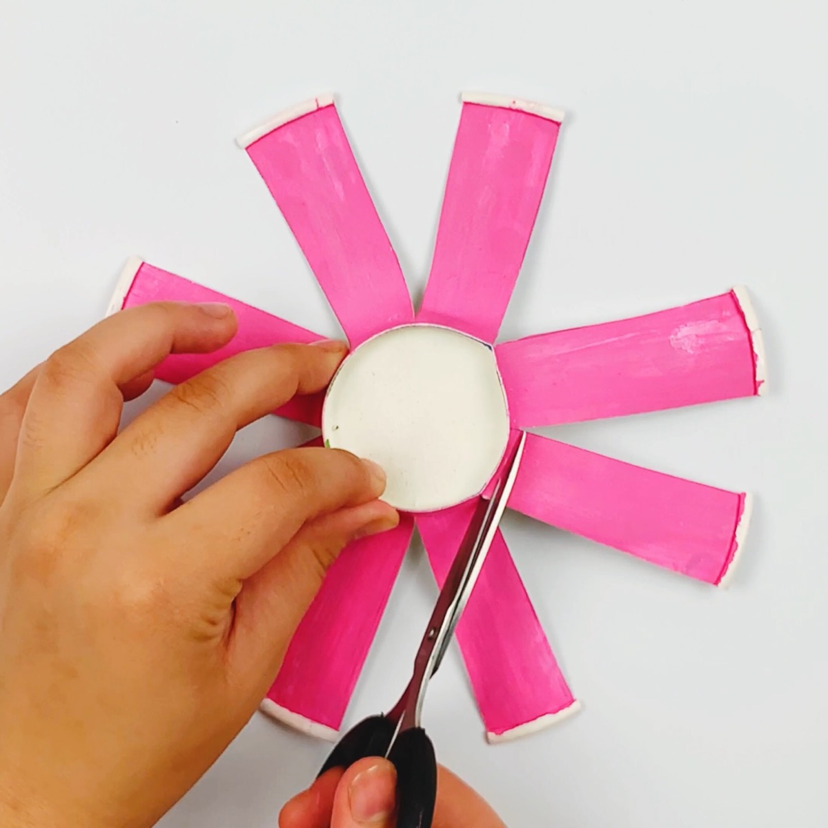 Cutting off four strips of the paper cup leaving just four in a plus sign shape along the base.