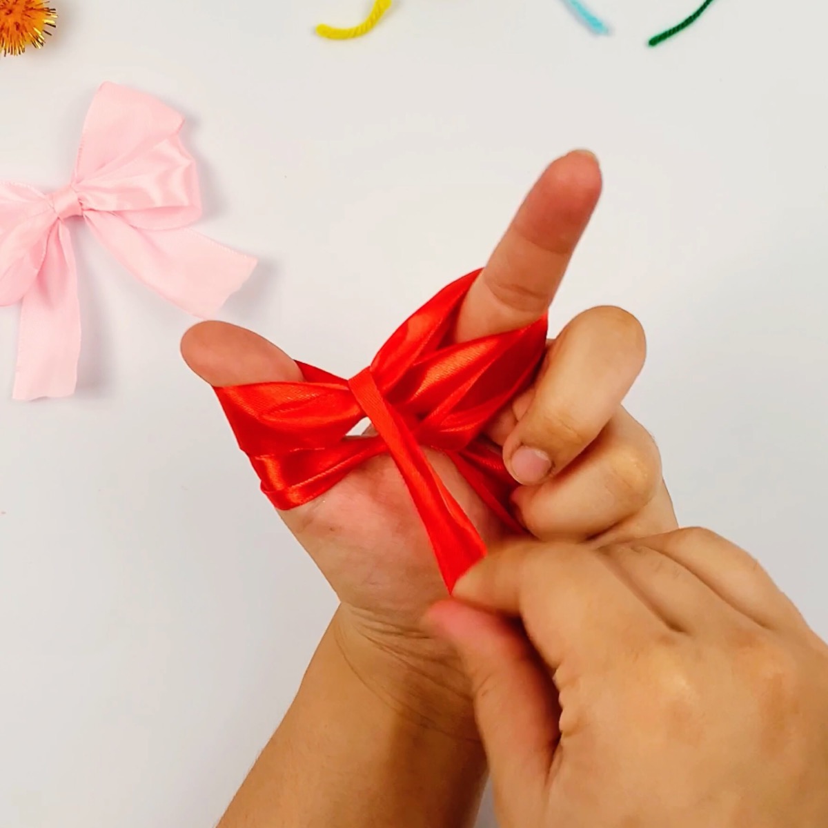 Step 8 of the ribbon bow making process showing how the ribbon is wrapped over the center of the two bows.