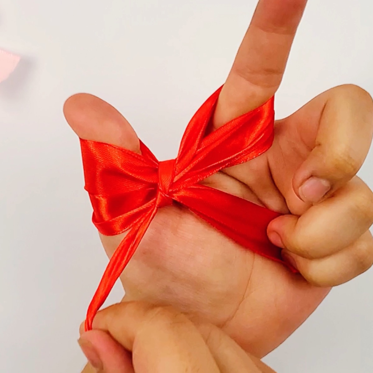 Step 10 of the ribbon bow making process showing how the left ribbon tassel is formed.