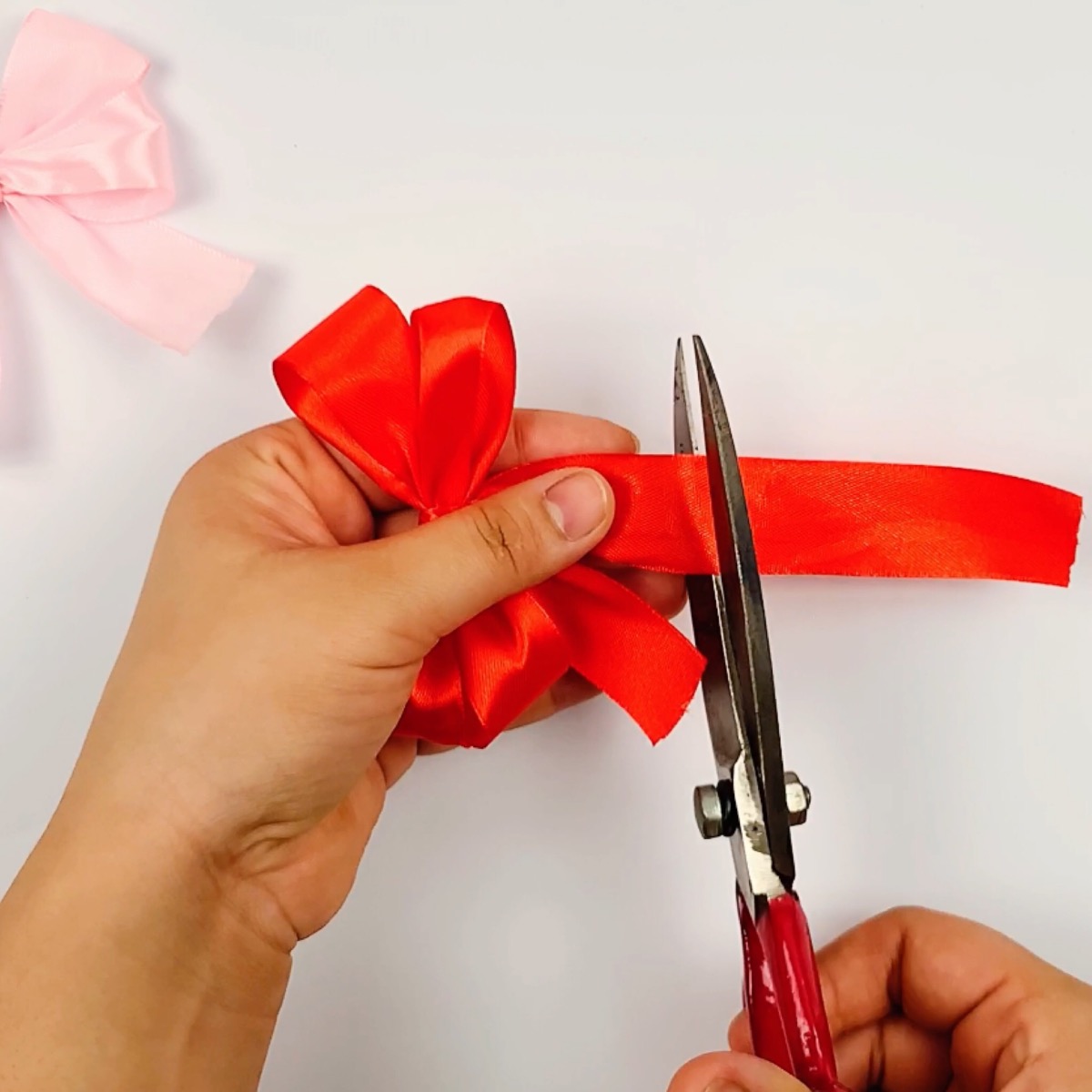 Step 11 of the ribbon bow making process showing how the ribbon tassels are cut to length.