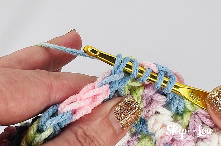 A multicolored yarn in yellow, blue, pink, purple, and white in a star stitch pattern.