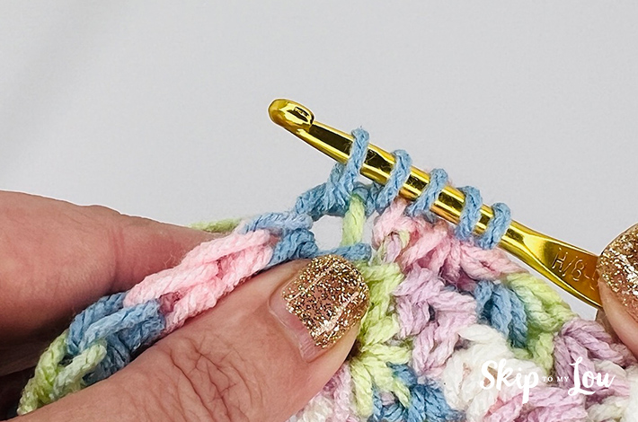 A multicolored yarn in yellow, blue, pink, purple, and white in a star stitch pattern.
