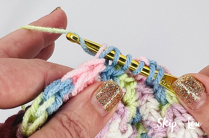 A multicolored yarn in yellow, blue, pink, purple, and white in a star stitch pattern.
