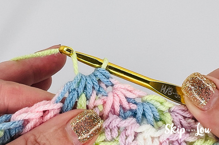 A multicolored yarn in yellow, blue, pink, purple, and white in a star stitch pattern.