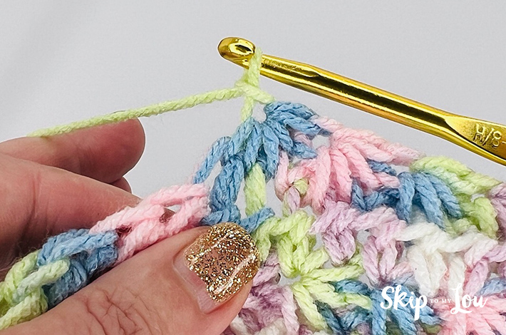 A multicolored yarn in yellow, blue, pink, purple, and white in a star stitch pattern.