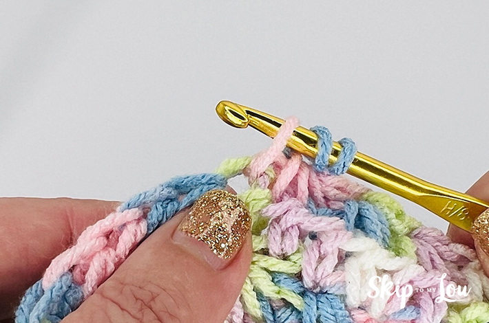 A multicolored yarn in yellow, blue, pink, purple, and white in a star stitch pattern.