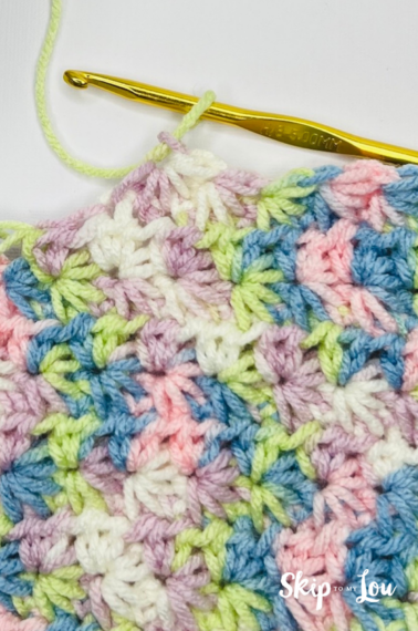A multicolored yarn in yellow, blue, pink, purple, and white in a star stitch pattern.