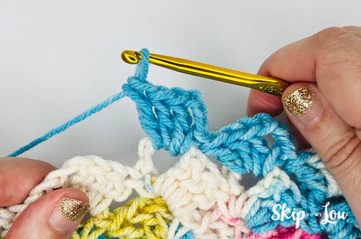 Hands holding a crochet needle showing how a traditional tulip stitch looks. 