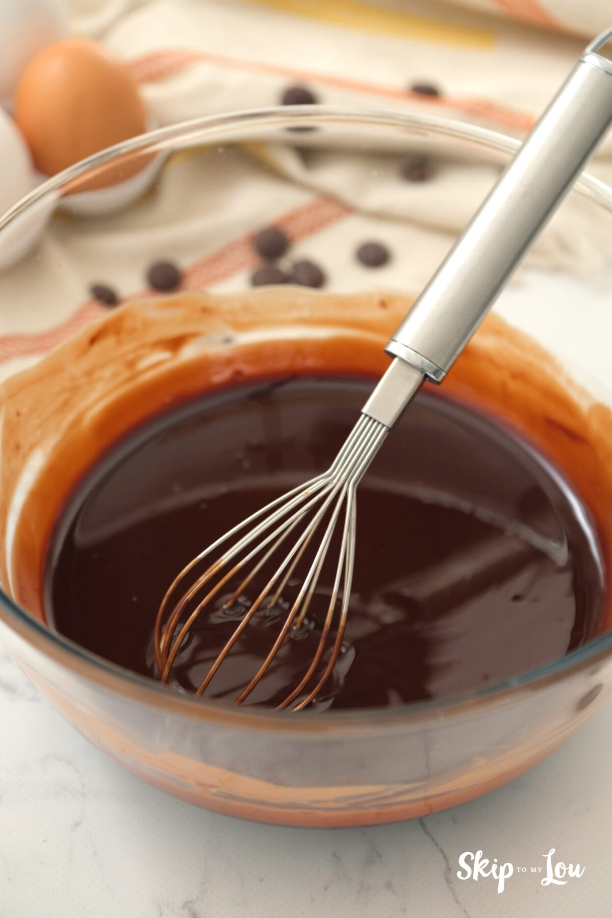 A bowl with a whisk and the chocolate chip and butter batter completely melted. 
