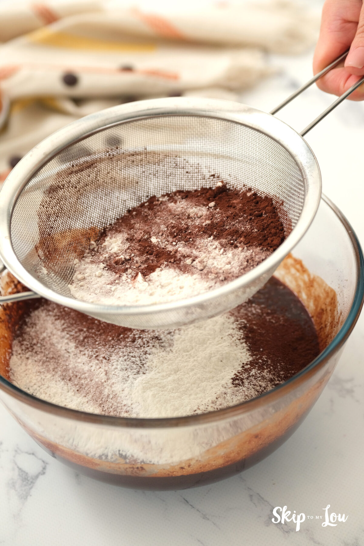 Flour and cocoa powder sifted into the bowl of batter. 