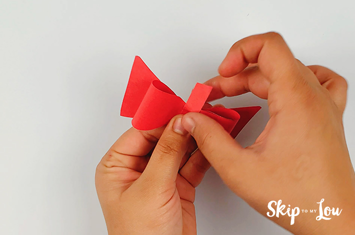The top end and the bottom of the paper are folded over the back of the bow tie.