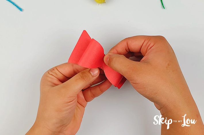 Two hands holding a completed red bow tie. 