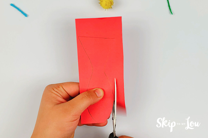 A pair of scissors being used to cut out the fish outline. 