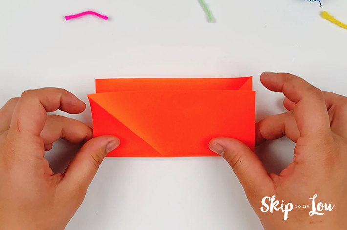 The square green paper is folded in half.