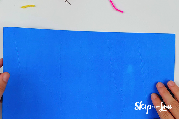 A blue letter sized piece of paper is the starting point for the origami shirt and tie.