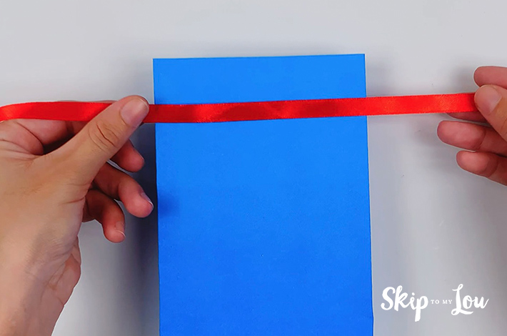 The ribbon that forms the tie for the origami shirt is placed just below the top of the paper.