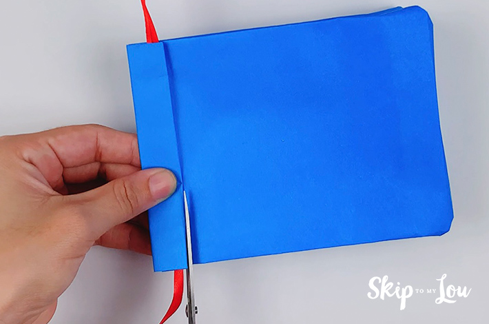 A small section of the paper is cut on the left below the top fold holding the ribbon for the tie.