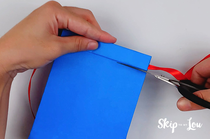 A small section of the paper is cut on the right, below the top fold holding the ribbon for the tie.
