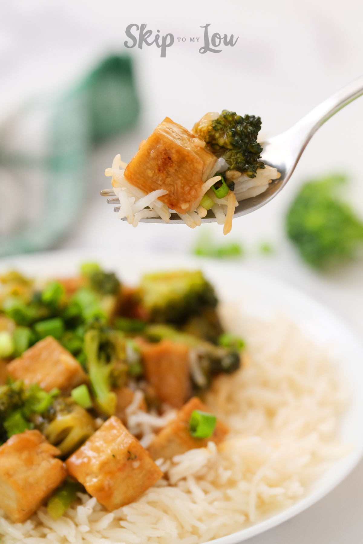 A plate of broccoli and tofu stir fry lying on a bed of rice from skip to my lou