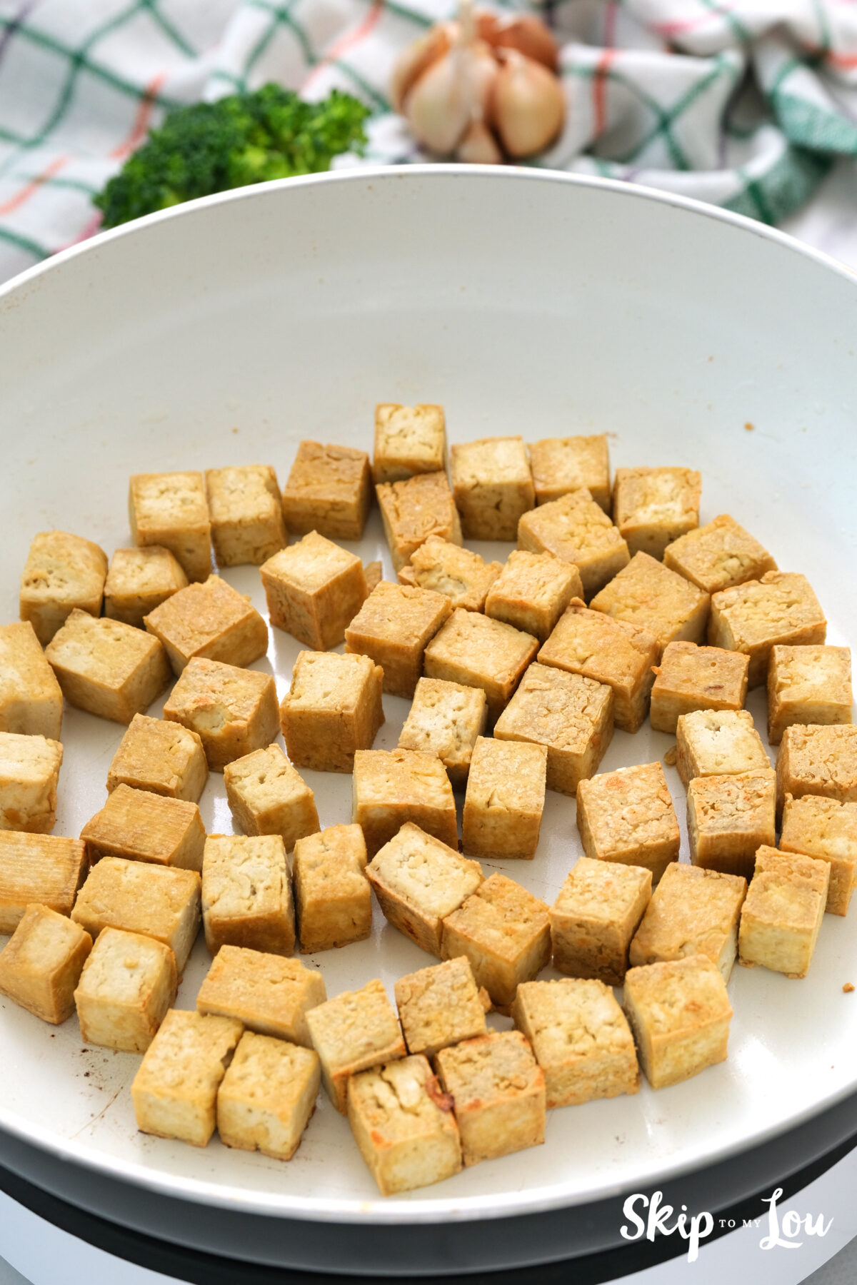 Tofu in a pan stir frying in vegetable and sesame oil.