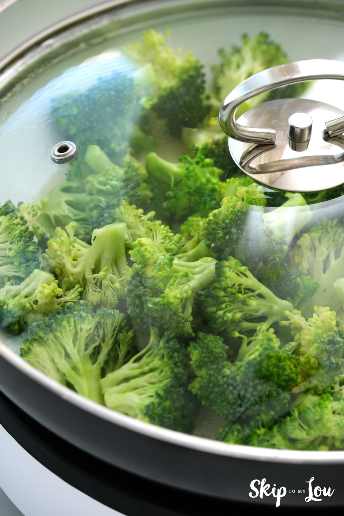 Broccoli steaming in a covered pan.