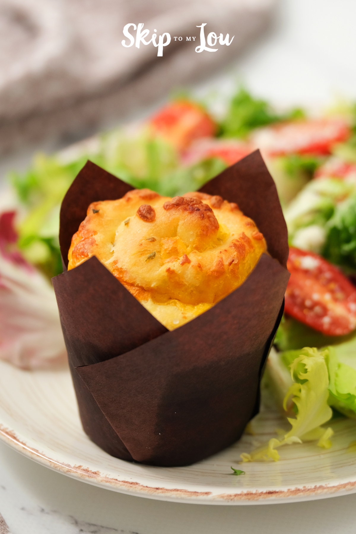 Baked herb roll on a white plate with a side salad from Skip to My Lou.
