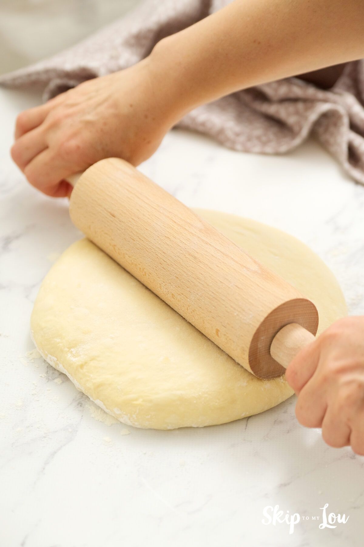 A rolling pin being used to roll out the dough.