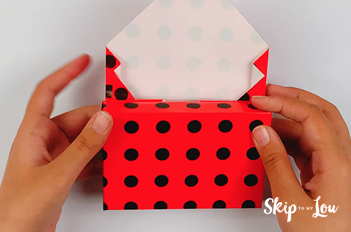 Two hands tucking the side of the wrapping paper inwards.