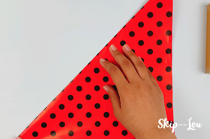 Two hands folding the paper in half to form a triangle.