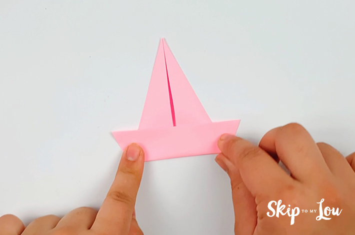 Two hands with the folded paper forming a silhouette of a sailing ship.