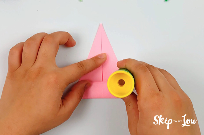 Two hands applying glue after the bottom section of the paper on the first spike has been unfolded.