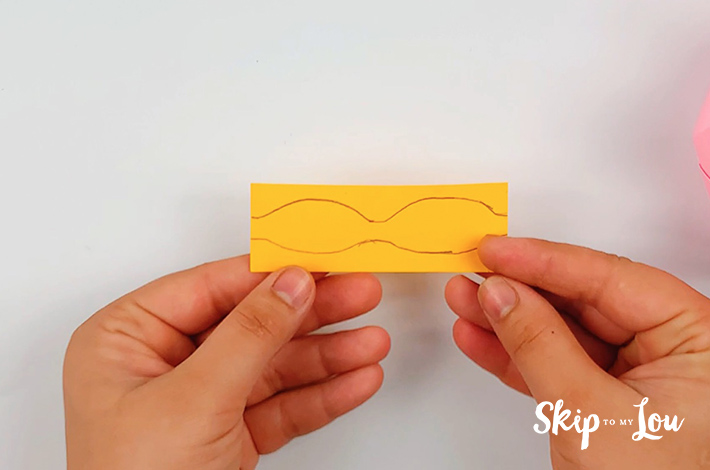 A rectangular piece of paper with a bow tie shape drawn on it. These will form the origami crown decorations.
