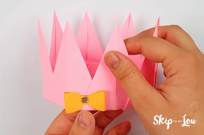 Two hands applying the decoration to the base of the origami crown.