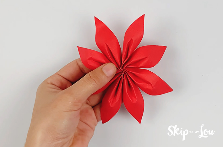 A hand holding the flower with all 8 petals glued together.