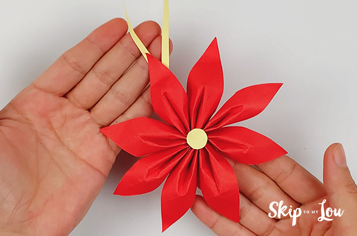 A ribbon is added to the origami flower which is now complete.